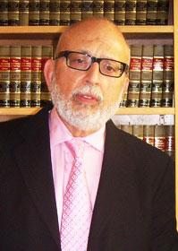 Dan Russo experienced jury trial attorney and criminal defense specialist featured at his law office in Vallejo california pink shirt and tie with law books from his vallejo office behind him.
